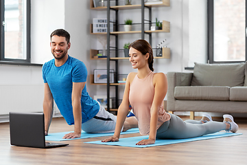 Image showing happy couple with laptop exercising at home