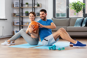 Image showing happy couple exercising with ball at home