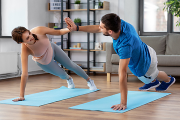 Image showing happy couple make high five in side plank at home