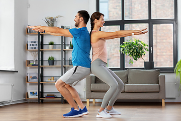 Image showing happy couple exercising and doing squats at home