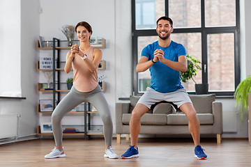 Image showing happy couple exercising and doing squats at home