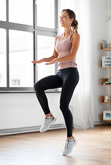 Image showing smiling young woman exercising at home