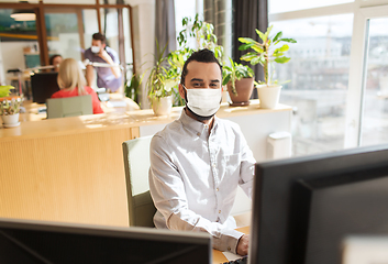 Image showing creative male office worker in mask with computer