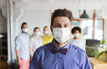 Image showing young man in mask over creative team at office