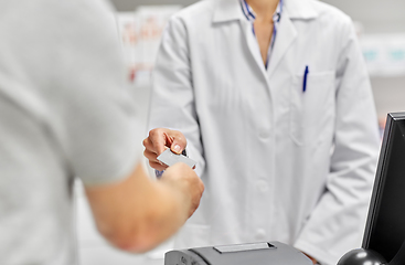 Image showing close up of hand giving bank card to pharmacist