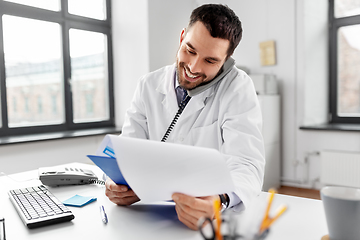 Image showing male doctor calling on desk phone at hospital