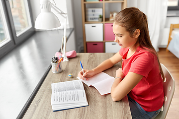 Image showing student girl with book writing to notebook at home