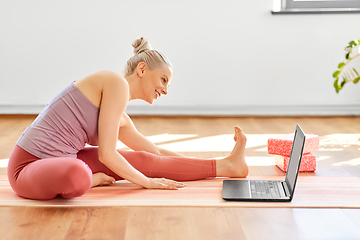 Image showing woman with laptop exercising at yoga studio