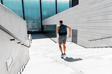 Image showing young man in headphones running downstairs