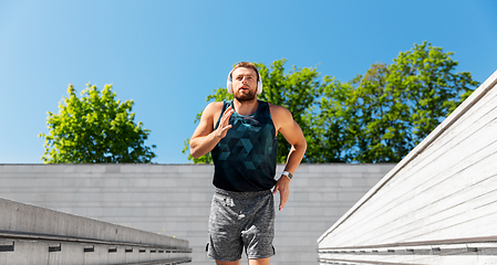 Image showing young man in headphones running outdoors