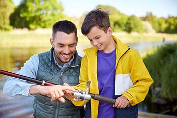 Image showing happy smiling father and son fishing on river