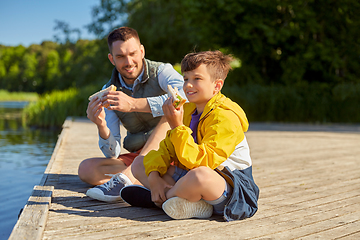 Image showing father and son eating sandwiches on river berth