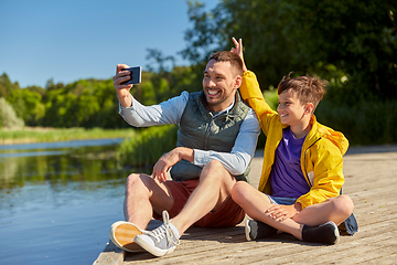 Image showing father and son taking selfie with phone on river