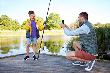 Image showing father photographing son with fishing rod on river