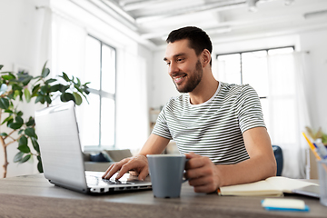 Image showing man with laptop drinking coffee at home office