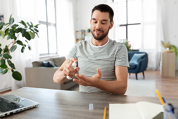 Image showing man using hand sanitizer at home office