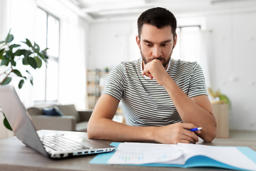 Image showing man with papers and laptop working at home office