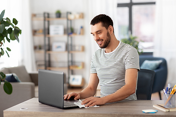 Image showing man cleaning laptop with wet wipe at home office