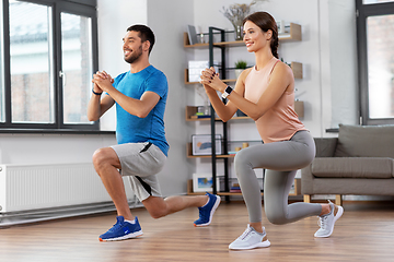 Image showing happy couple exercising and doing squats at home