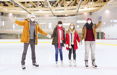 Image showing friends in masks waving hands on skating rink