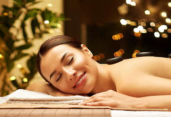 Image showing smiling woman having hot stone massage at spa