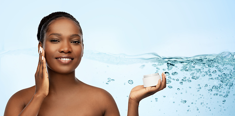 Image showing smiling african american woman with moisturizer