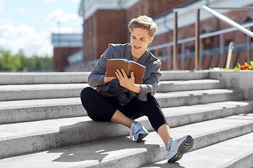 Image showing young man or teenage boy reading book in city