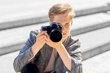Image showing young man with camera photographing in city