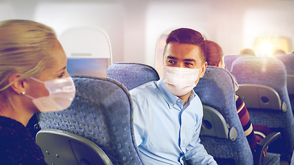 Image showing passengers in masks talking in plane