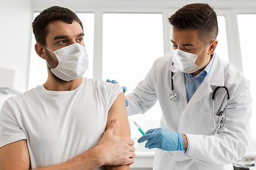 Image showing patient and doctor in masks doing vaccination