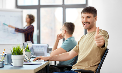Image showing happy man showing thumbs up at office