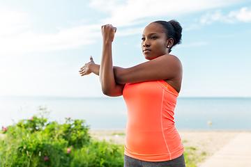 Image showing young african american woman stretching on beach