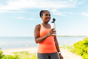 Image showing african american woman drinking water after sports