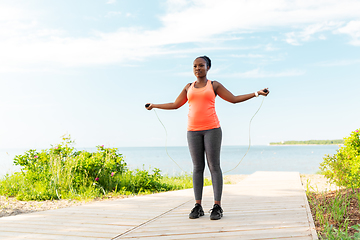 Image showing african woman exercising with jump rope on beach