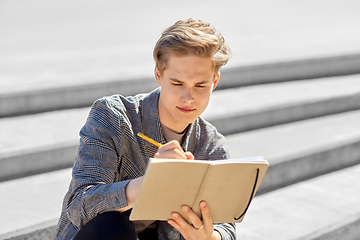 Image showing young man with notebook or sketchbook in city