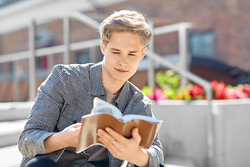 Image showing young man or teenage boy reading book in city