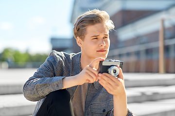 Image showing young man with camera photographing in city