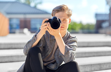 Image showing young man with camera photographing in city