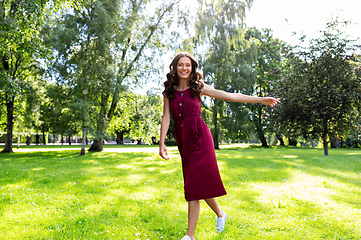 Image showing happy smiling woman walking along summer park