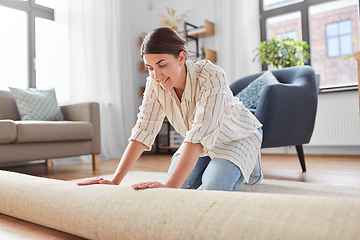 Image showing young woman unfolding carpet at home