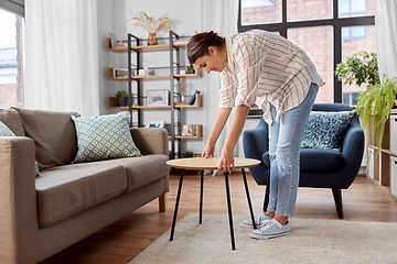 Image showing woman placing coffee table next to sofa at home