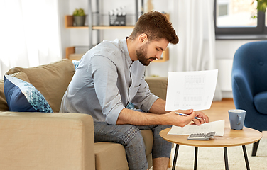 Image showing man with bills counting on calculator at home