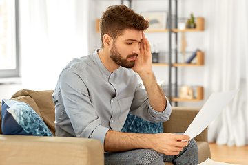 Image showing unhappy man with bills or tax report at home