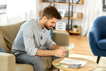 Image showing man with money and calculator filling papers