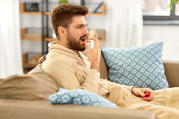 Image showing sick indian man using oral spray at home