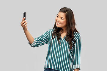 Image showing smiling asian woman taking selfie by smartphone