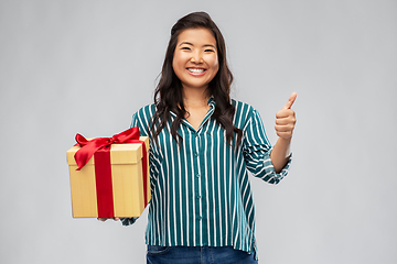 Image showing happy asian woman with gift box showing thumbs up