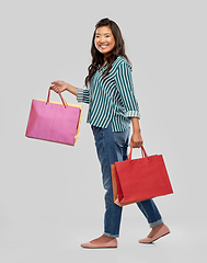 Image showing happy asian woman walking with shopping bags