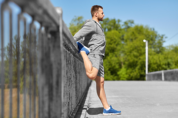 Image showing man stretching leg on bridge