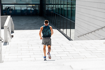 Image showing young man in headphones running downstairs